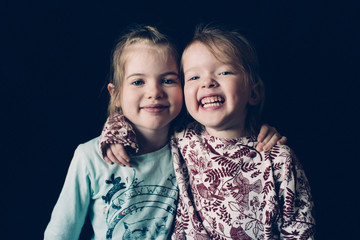 Portrait of little happy  girls sisters, isolated,on a dark  background