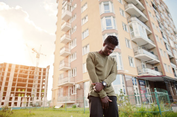 Handsome and attractive african american man posing next to the tall building on a street.