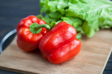 Red pepper and fresh salad as background on the wooden board