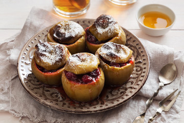 Baked apples with cranberries and sugar powder on a plate