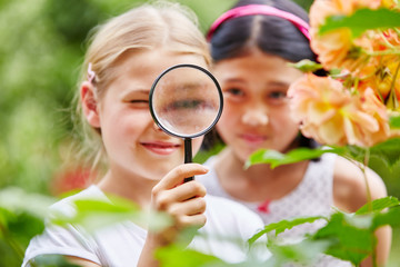 Mädchen betrachten Blumen durch  Lupe