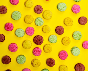 Multicolored macarons on the yellow background