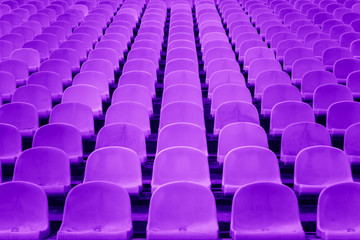 Obraz premium Chairs in the stadium symmetrical and textured painted in violet. Perspective and symmetry. Abstract wallpaper. 