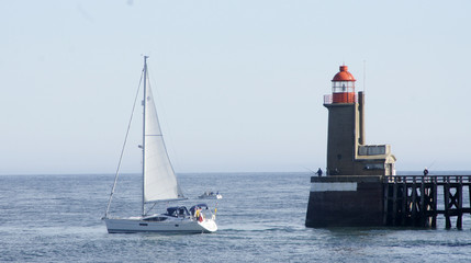 Fototapeta na wymiar Vue sur un phare en bretagne avec des bateaux qui passent devant