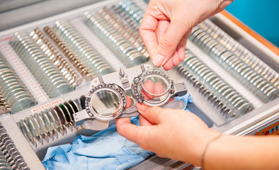 Optician female hands choose lenses from set of corrective lens indicating on the plates of the...
