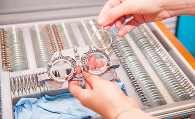 Optician female hands choose lenses from set of corrective lens indicating on the plates of the...