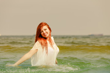 Redhead woman playing in water during summertime