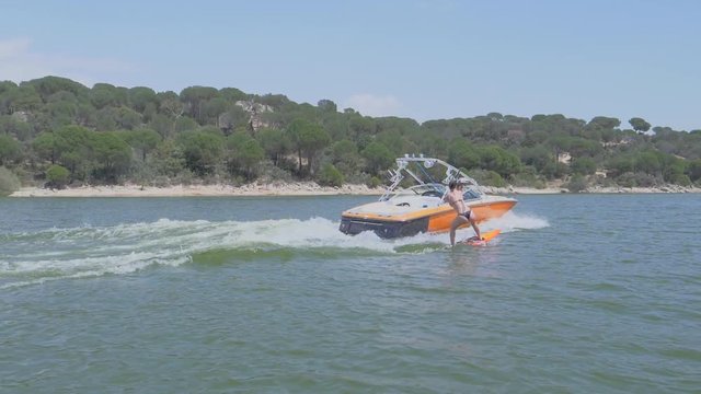 Girl practicing wakeboard with an orange boat in a swamp slow motion 2