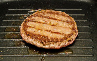 Home made cuisine delicious raw beef meat burger in a frying pan on cooking surface in kitchen