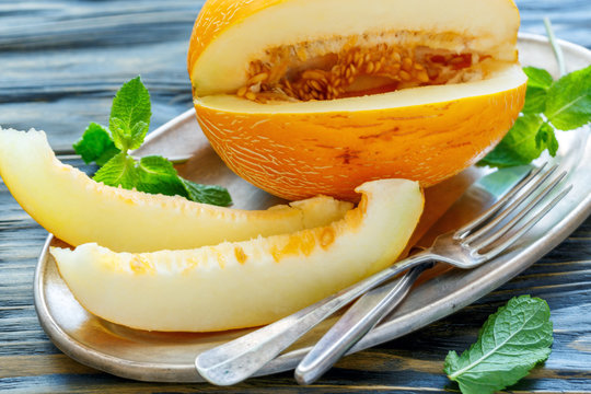 Dish with ripe yellow melon and cutlery.