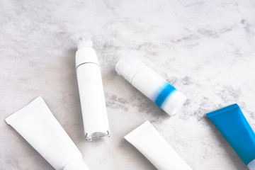 Skincare cosmetic products from above on white marble table. Cream, cleancer, moisturizer, lotion. Branding mock up. 