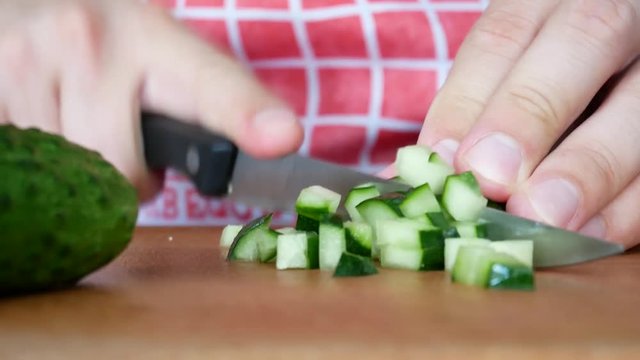 Cutting Tasty Green Cucumber on Chopping Board With Knife. Cooking Salad in Home Kitchen. Chefcook are Chopping Slices Cucumber. Hands Sliced Cucumber In Vegan Salad. Diet And Healthy Food