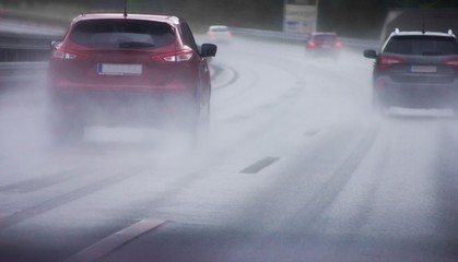 Cars driving on wet rainy road in bad weather 