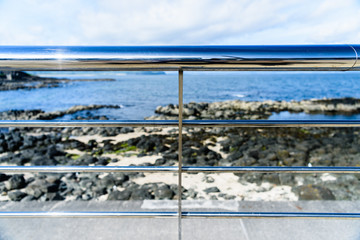 Stainless steel railings along a seafront.