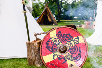 Sword, axe and shield belonging to a medieval soldier beside a fire at an army camp site.