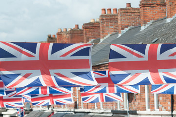 Many union flags hanging above a British street during a celebration.