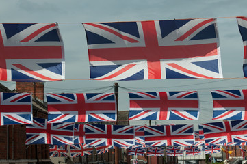 Many union flags hanging above a British street during a celebration.