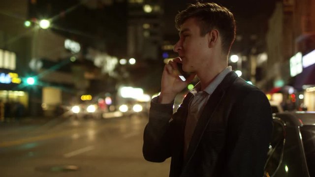 Young happy man is talking over his mobile phone on a street at night