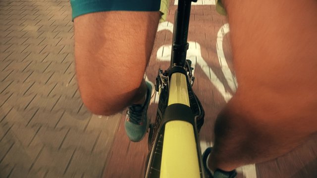 POV Of Pedaling Male Legs. Man Cycling Along City Bike Path