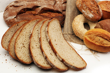 Different kinds of bread and bread rolls on board from above. Kitchen or bakery poster design.