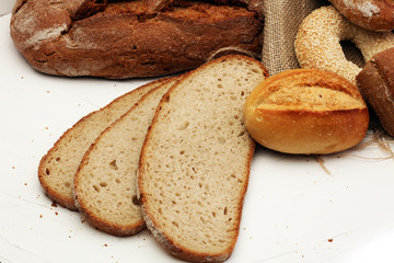 Different kinds of bread and bread rolls on board from above. Kitchen or bakery poster design.