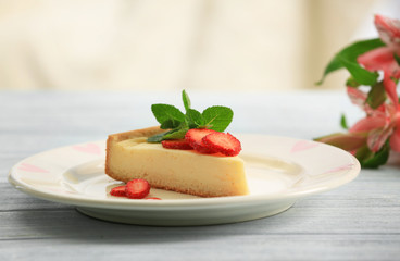 Plate with delicious cheesecake and sliced strawberry on wooden table
