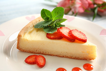 Plate with delicious cheesecake and sliced strawberry, closeup