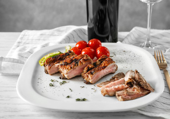 Yummy grilled spare ribs with cherry tomatoes on square white plate