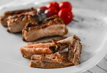 Yummy grilled spare ribs with cherry tomatoes on square white plate
