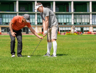 Obraz premium Caddy teaching young man to play golf on course in sunny day