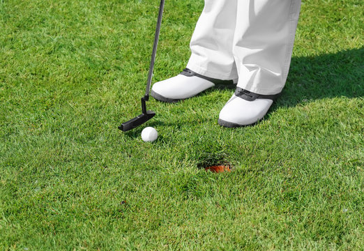Legs of young man playing golf on course in sunny day