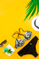 Tropical vacation and beach sand theme yellow colored background with with bucket hat, sunglasses and dark green palm tree leaves