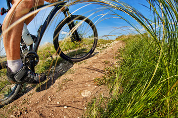 Naklejka premium cyclist man feet riding mountain bike on outdoor trail in sunny meadow