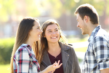 Three happy friends talking in the street