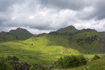 Горный пейзаж, красивые зеленые склоны в живописном ущелье, облачное небо. Природа и горы Северного Кавказа