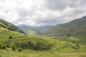 Naklejka premium Górski krajobraz, piękne zielone stoki w malowniczym wąwozie, zachmurzone niebo. Przyroda i góry Kaukazu Północnego