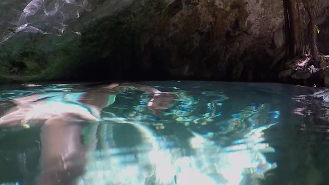 Slow motion close up, underwater young woman cavern diving and exploring the breathtaking beauty of an ancient cave
