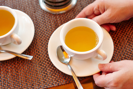 Two cups of tea, female hands holding a cup of tea