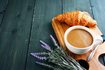 Coffee cup and croissant on table.