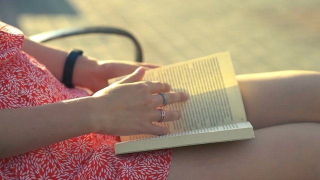girl reading book at park in summer sunset light.
