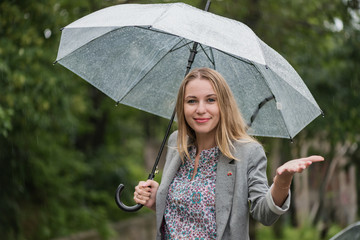 Beautiful girl is wet under the rain. Girl with an umbrella in bad weather