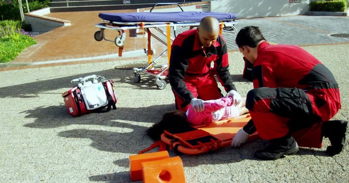 Paramedics putting injured girl onto a backboard