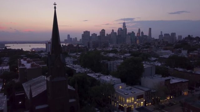 dusk flying past Brooklyn church towards Manhattan skyline