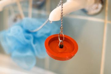Red rubber bath plug on chain