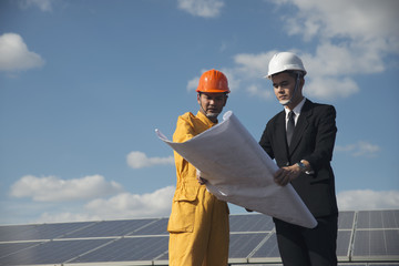 Professional electrical engineer Manager wear safety yellow helmet serious discuss about maintenance,pointing Blueprint  with Business man at solar plant with better work. Electrical Engineer concept.