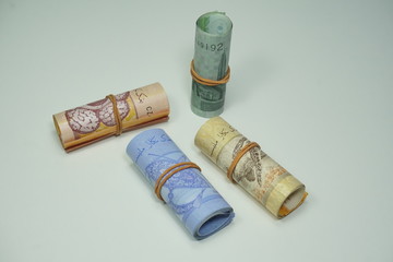 Malaysian Ringgit (MYR) ringgit paper roll tied with a rubber band on a wooden background.