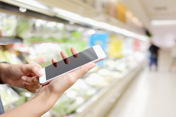 Woman hands using mobile phone in supermarket.