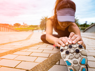 female runner stretching legs before running and doing workout at outdoor park  on sunset background