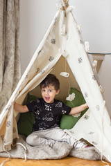 Toddler boy playing in a teepee © Anna