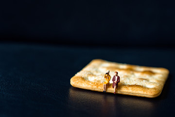 Miniature people, couple woman sitting on biscuit using for business human resource concept